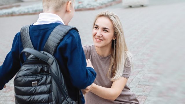 Foto: Shutterstock. Bildet viser en mor som hjelper sin sønn med skolesekk.