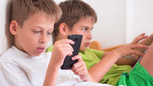 Foto: Shutterstock. To gutter spiller med mobil og nettbrett.
