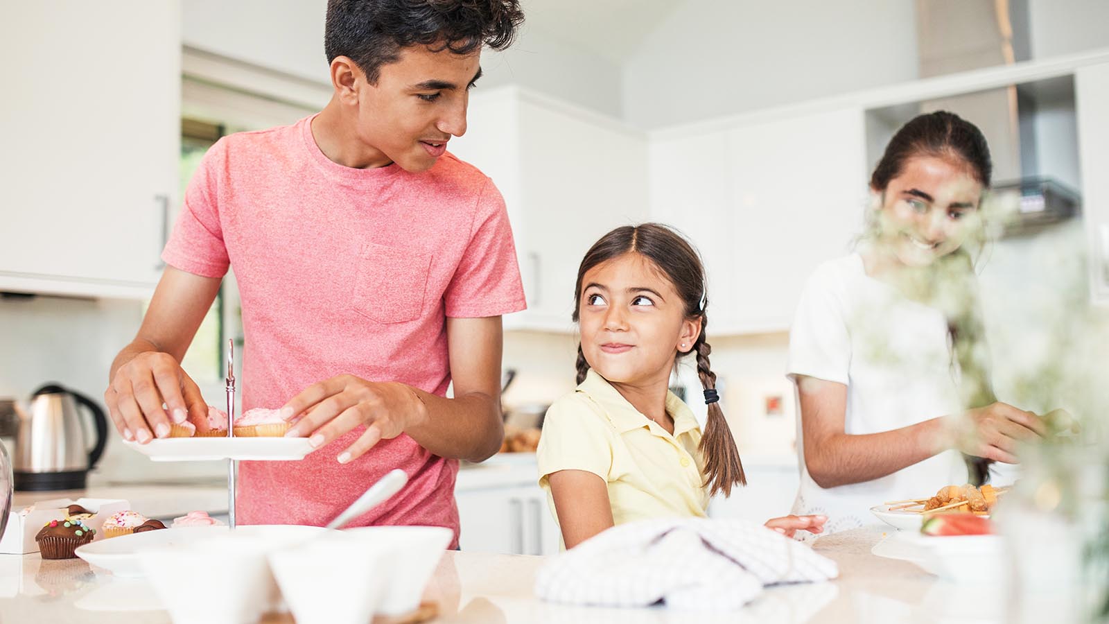 Tre barn lager mat på kjøkkenet. Foto: Shutterstock.