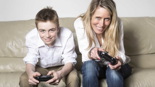 Foto: Shutterstock. Mor og barn spiller dataspill. Sitter i sofa.