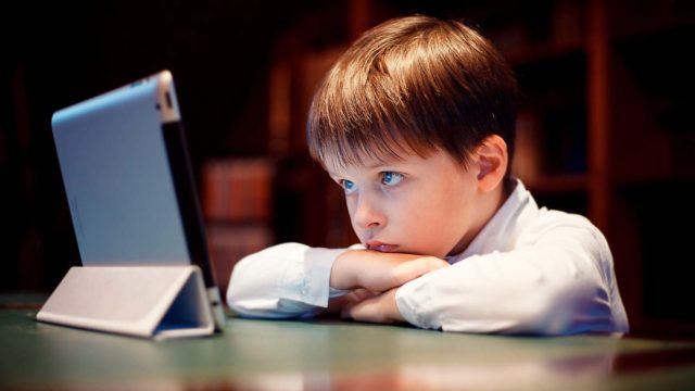 Gutt ser på et nettbrett. Foto: Shutterstock.