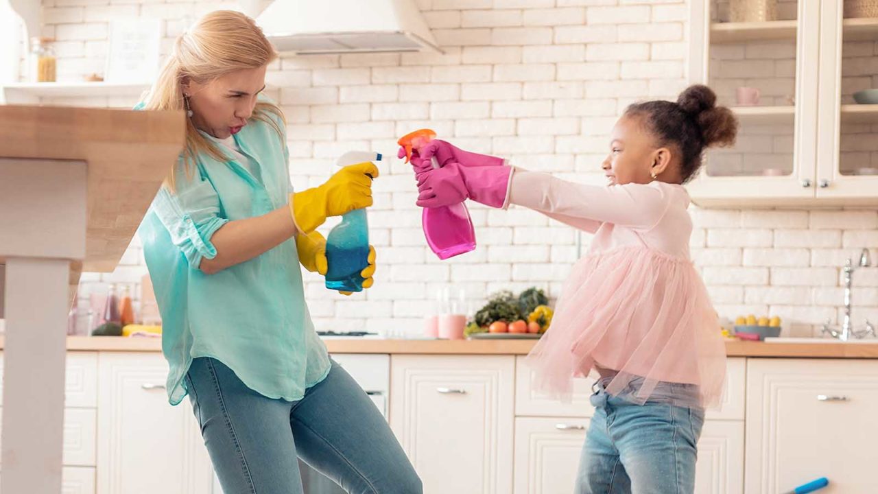 Mor og datter leker krig og spruter på hverandre med såpeflasker på kjøkkenet. Foto: Shutterstock
