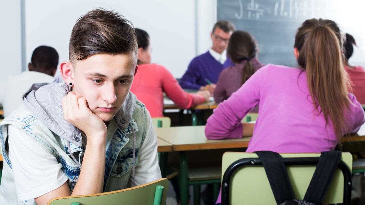 Foto: Shutterstock. Gutt sitter trist i et klasserom.