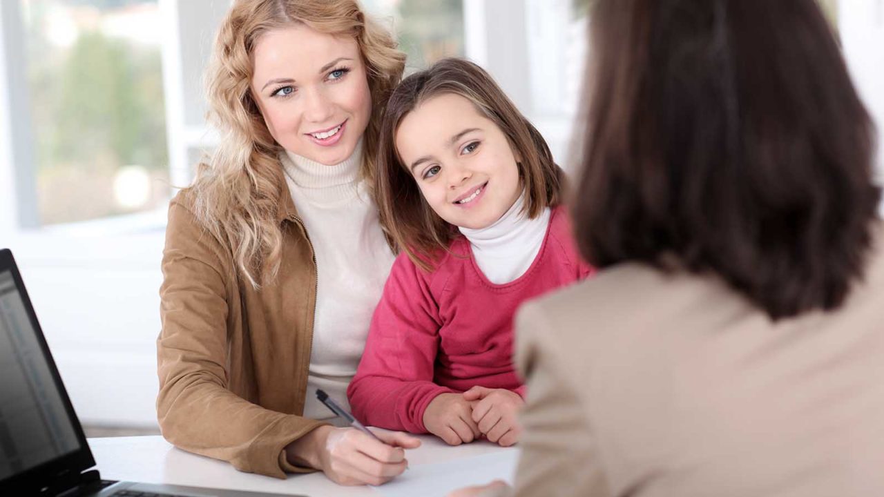 Foto: Shutterstock. Bildet viser en mor med sitt barn, moren er i ferd med å signere en avtale.