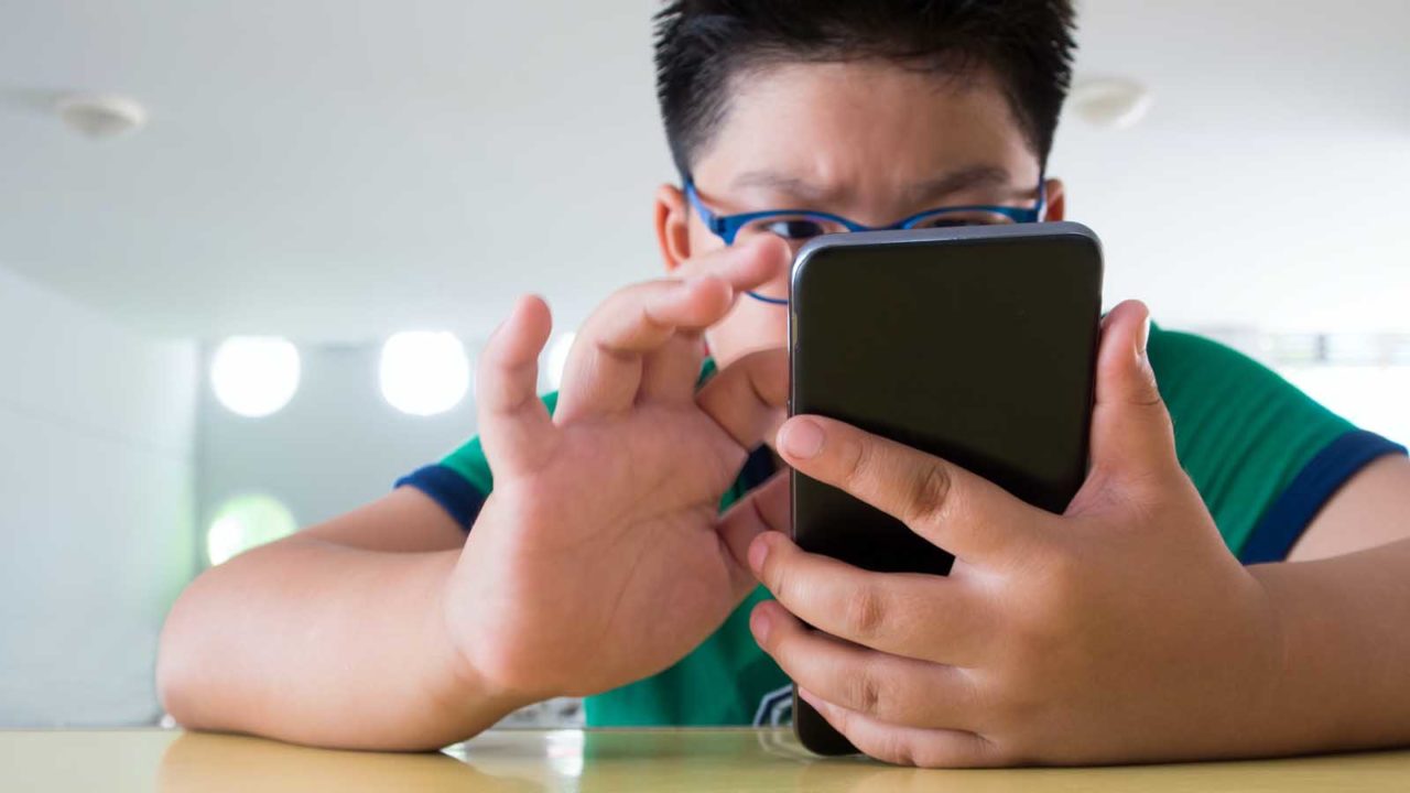 Foto: Shutterstock. Bildet viser en gutt med mobiltelefon.