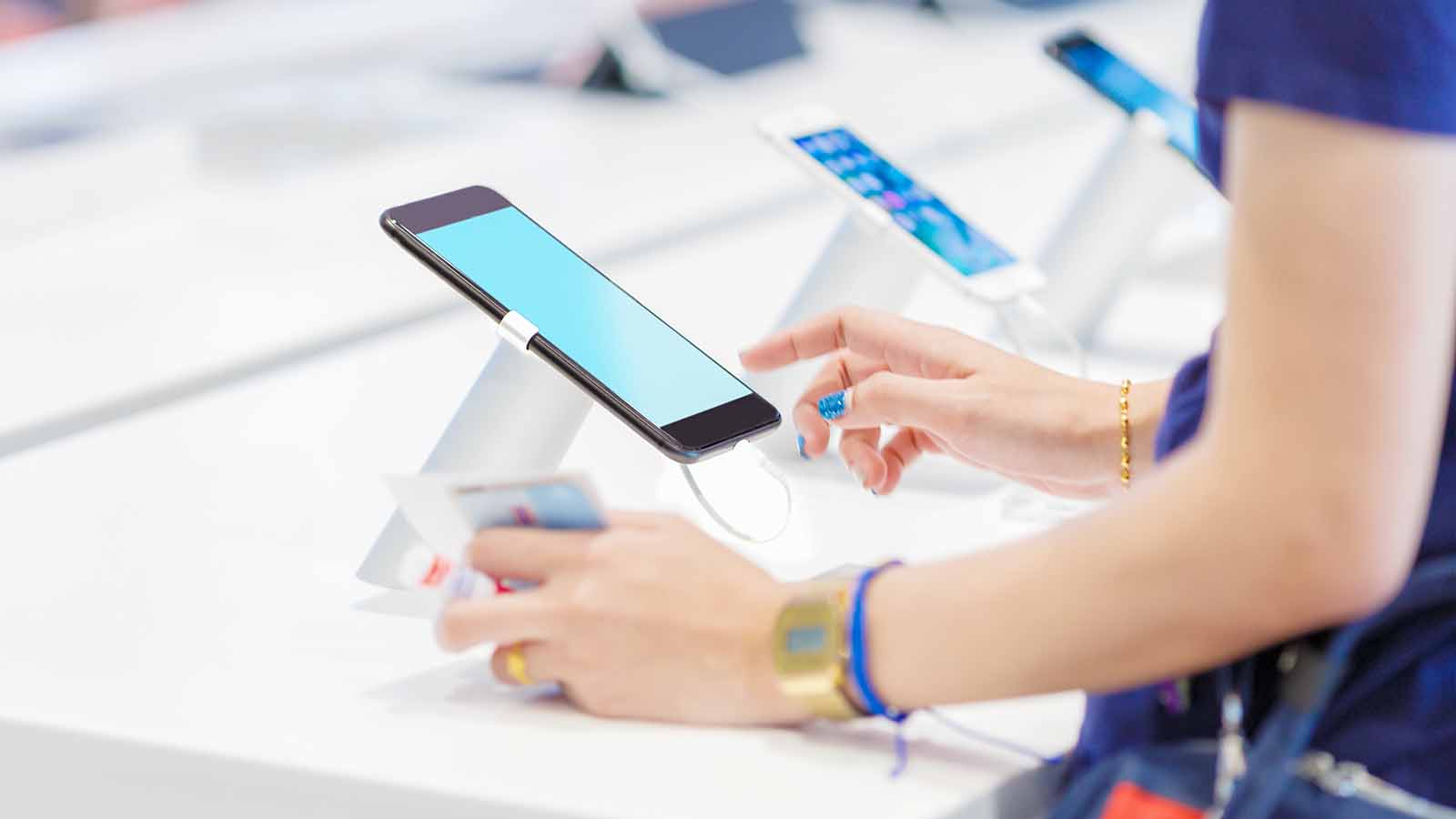 Foto: Shutterstock. Bildet viser en kvinne som prøver en telefon i en butikk.