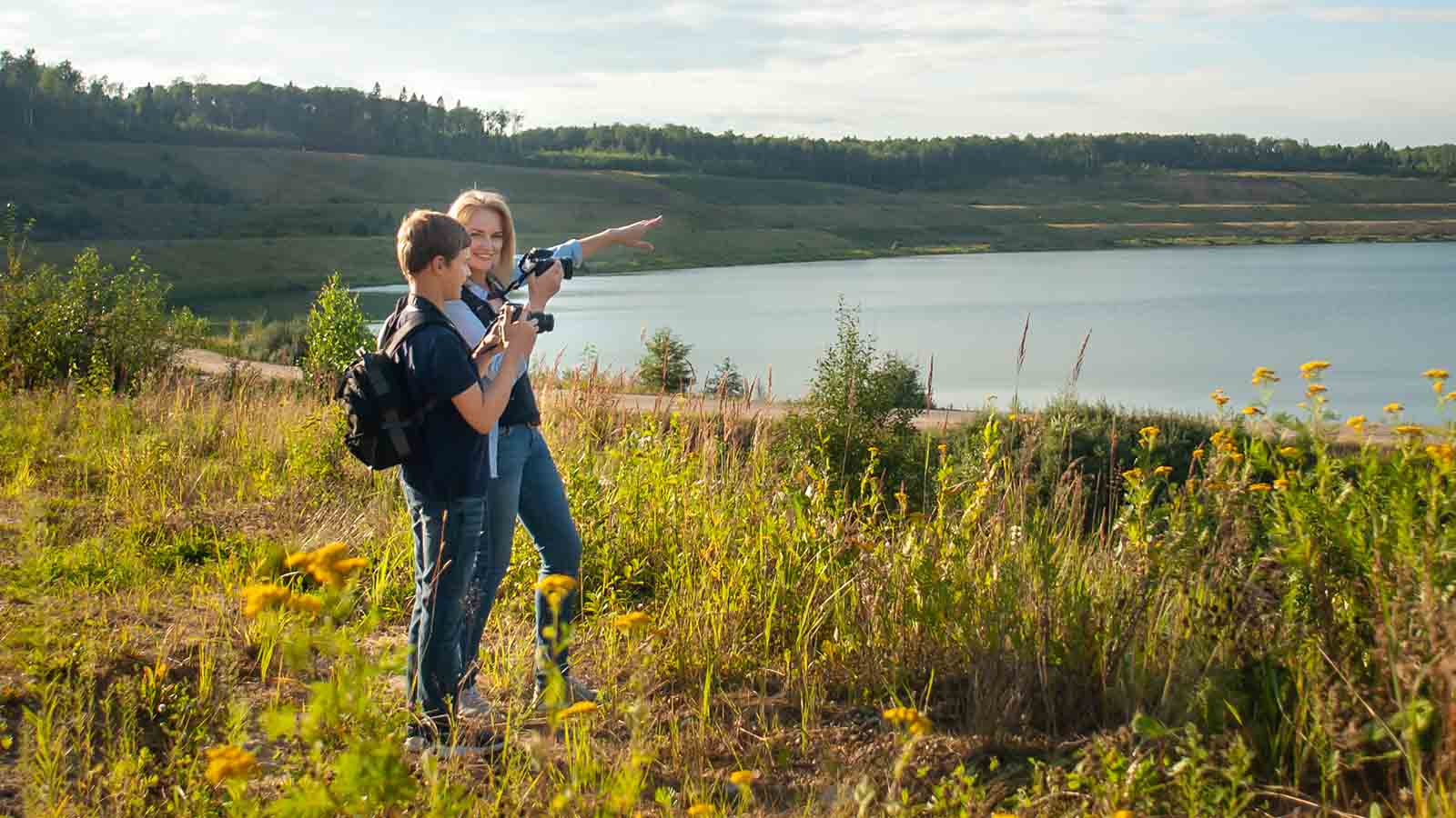 Foto: Shutterstock. Bildet viser mor med sønn ved det et vann, de har begge kamera.