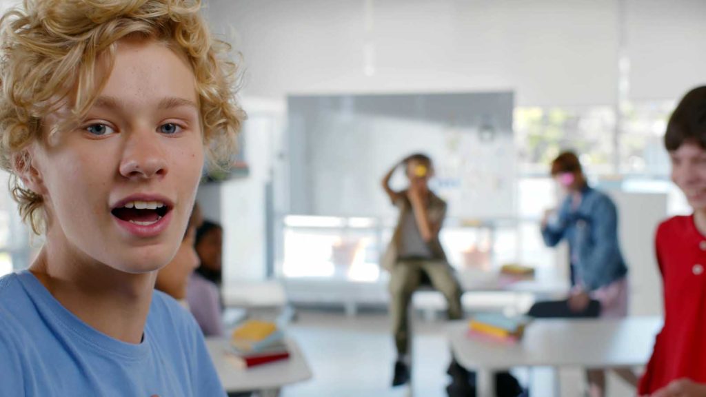 Foto: Shutterstock / nimito. Bildet viser tenåringsgutter i et klasserom. Bakerst er det en gutt som filmer med mobiltelefon.