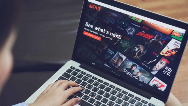 Foto: Shutterstock / Sitthiphong. Bildet viser en kvinne med en PC, på skjermen er Netflix.