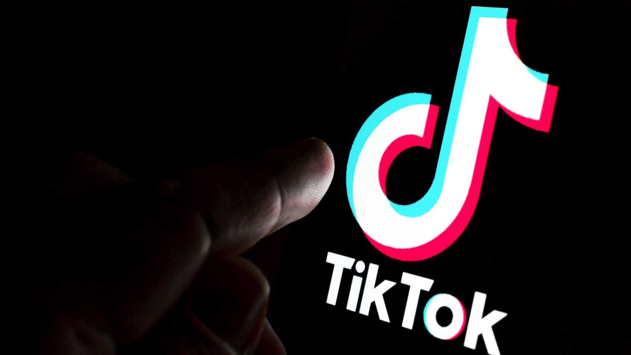 Foto: Shutterstock / Ascannio. Bildet viser en finger som peker mot en telefon med Tiktok-logo.