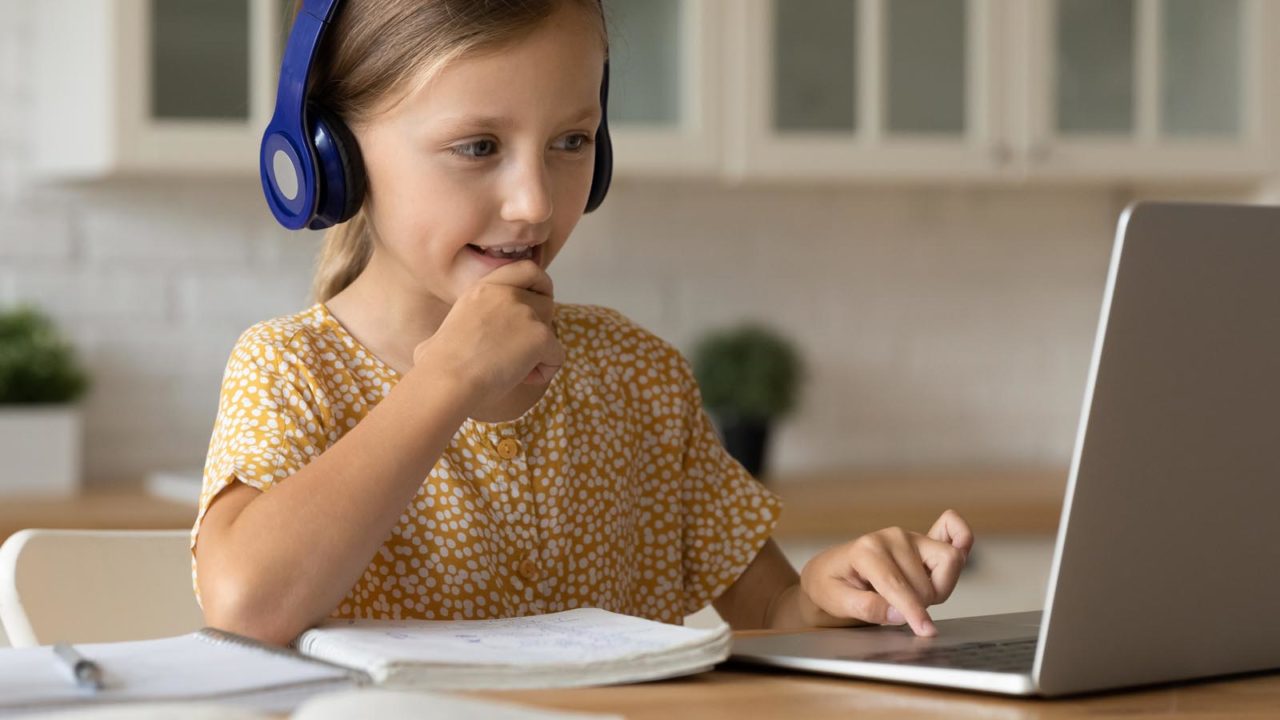Foto: Shutterstock / fizkes. Bildet viser ei jente med hodetelefoner og datamaskin.