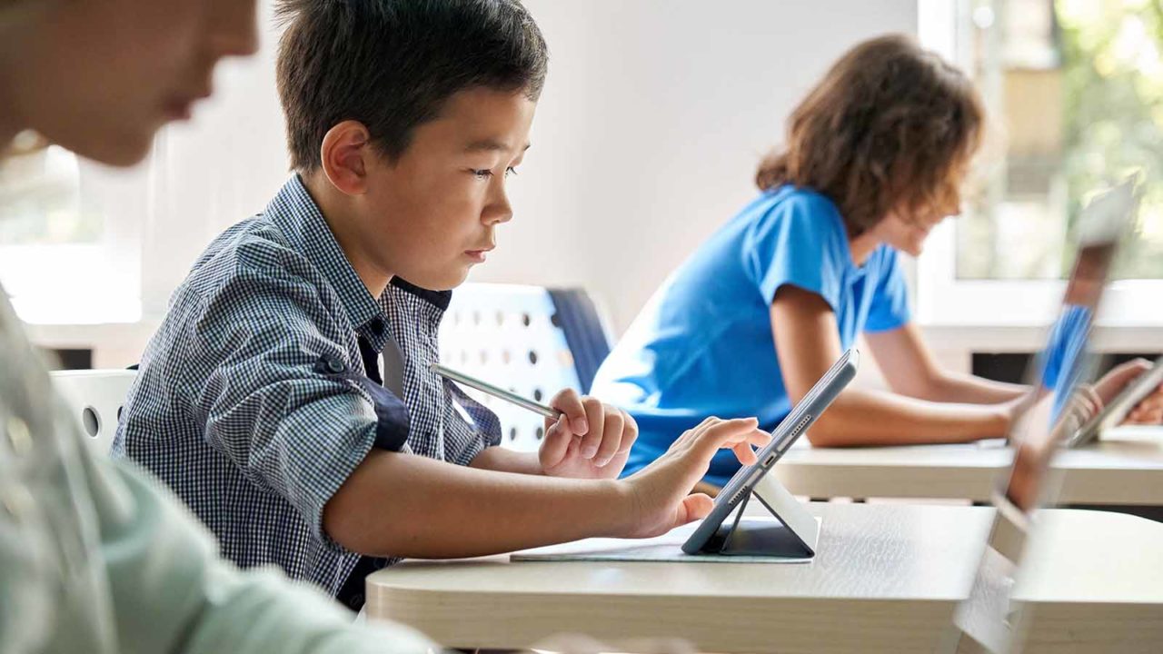 Foto: Shutterstock / insta_photos. Bildet viser en gutt med datamaskin på skolen.