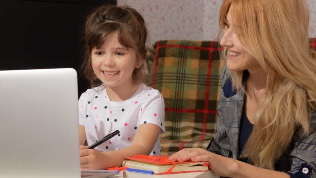 Foto: Shutterstock / Yuliia D. Bildet viser en mor og en datter foran en datamaskin.