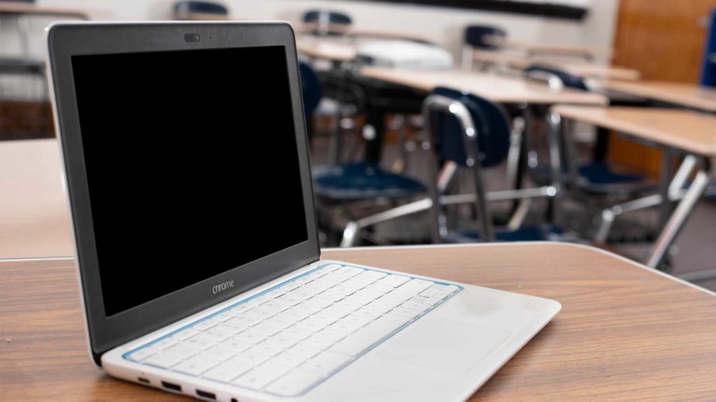 Bildet viser en datamaskin som står på en skolepult.