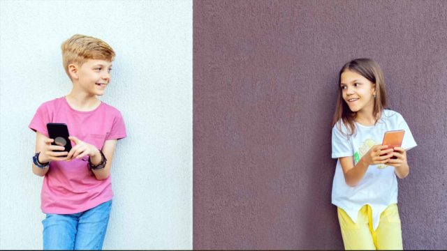 Foto: Shutterstock / Dan Rentea. Bildet viser en gutt og ei jente med hver sin telefon. De ser på hverandre.