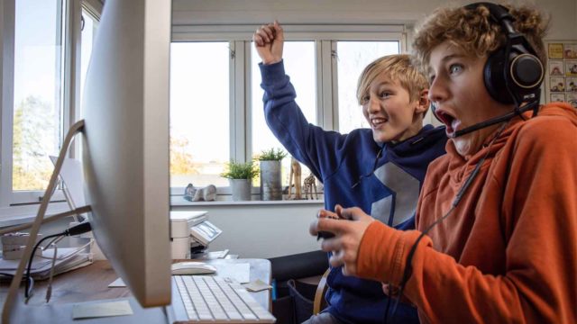 Bildet viser to tenåringsgutter som spiller på datamaskin.