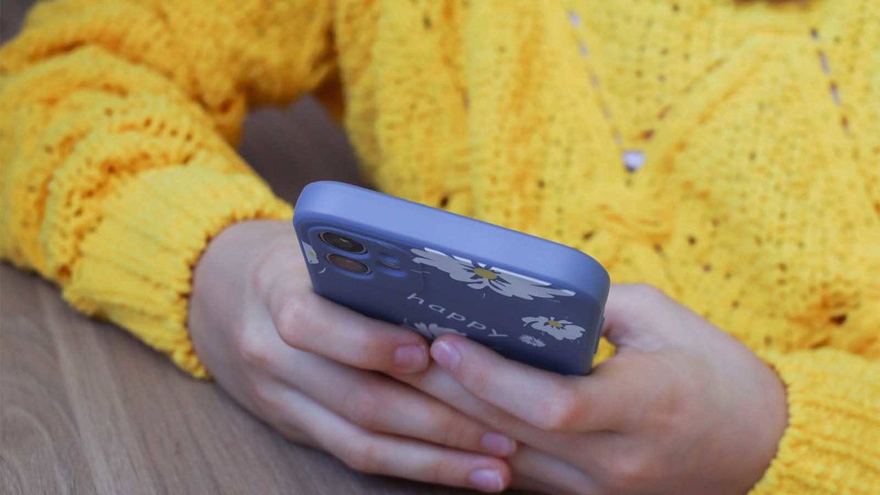 Foto: Shutterstock / Kate_Geras. Bildet viser ei jente som holder en telefon. Man ser kun hendene, telefonen og genseren.