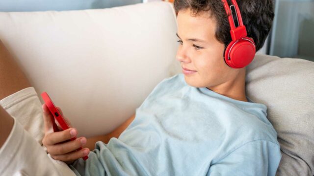 Foto: Shutterstock / Laugesen Mateo. Bildet viser en gutt med høretelefoner og mobiltelefon.