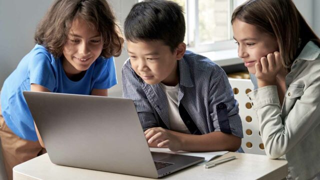 Foto: Shutterstock / Ground Picture. Bildet viser tre elever som kikker på en dataskjerm.