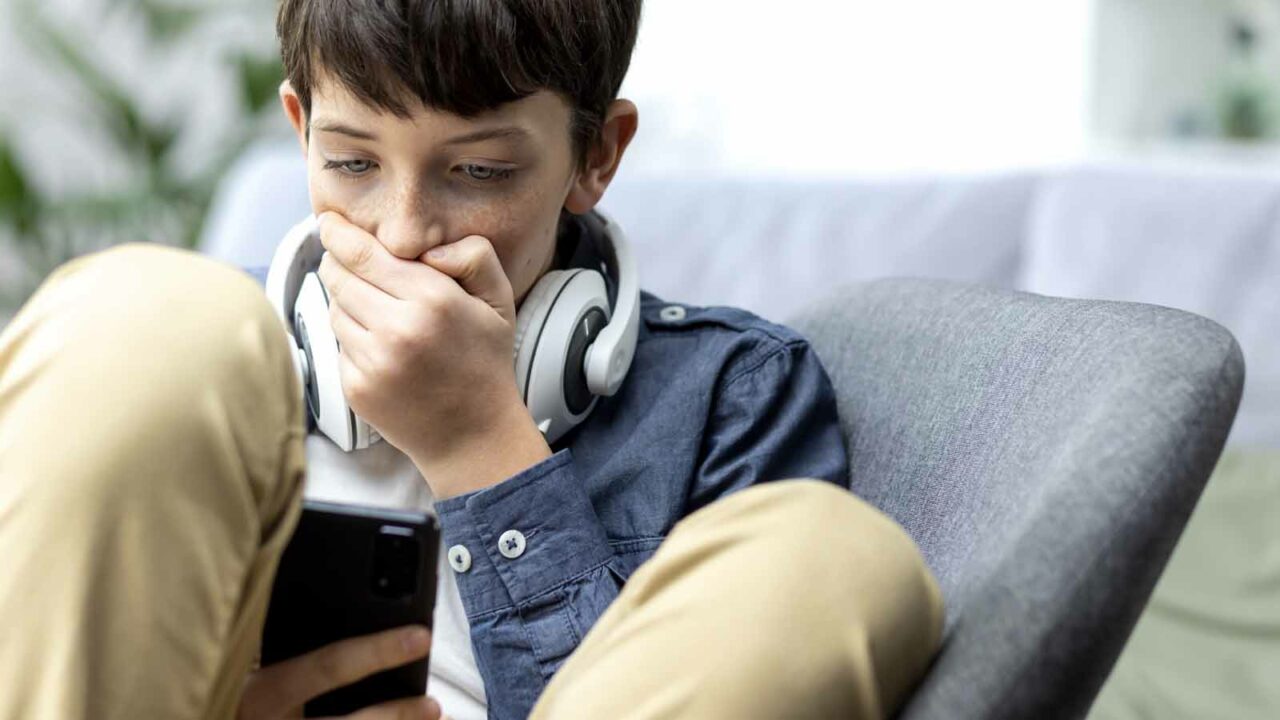 Foto: Shutterstock / voronaman. Bildet viser en tenåringsgutt som er sjokkert over hva han ser på telefonen.