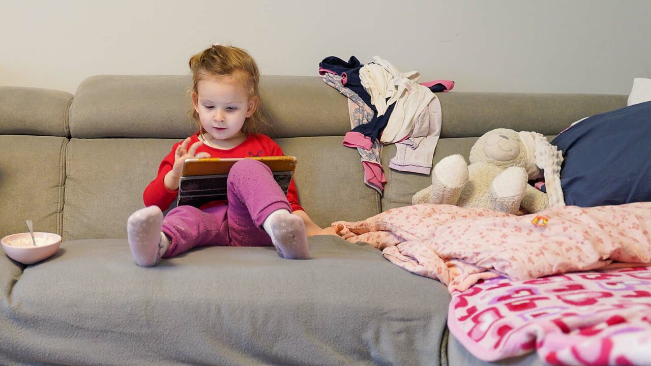Foto: Shutterstock / Phoenixns. Bildet viser ei jente som sitter i sofaen hjemme og ser på et nettbrett.